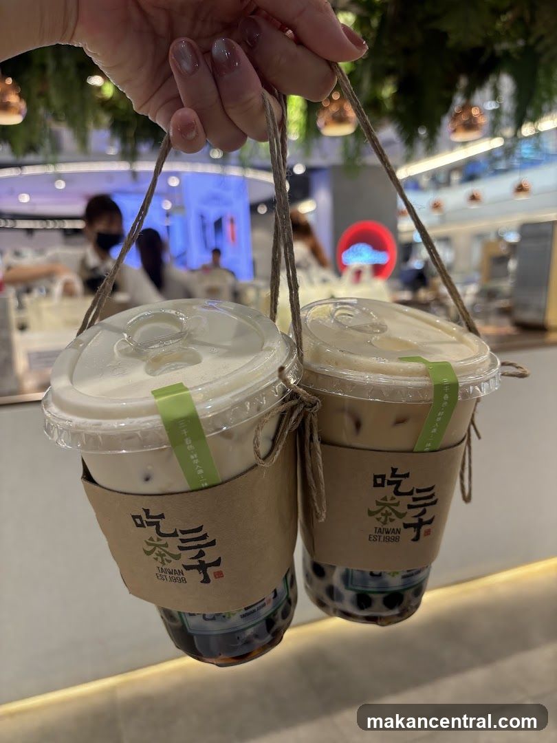Two bubble tea cups held by hand