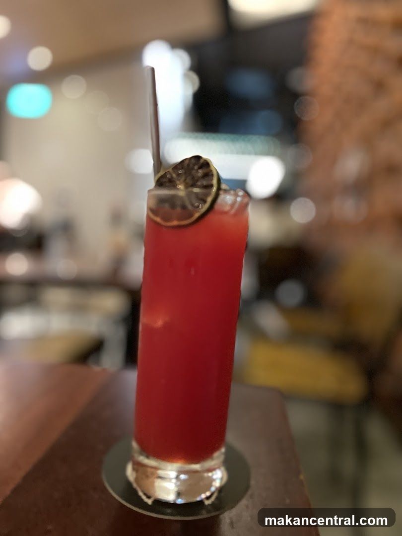 Red beverage in tall glass with lime garnish