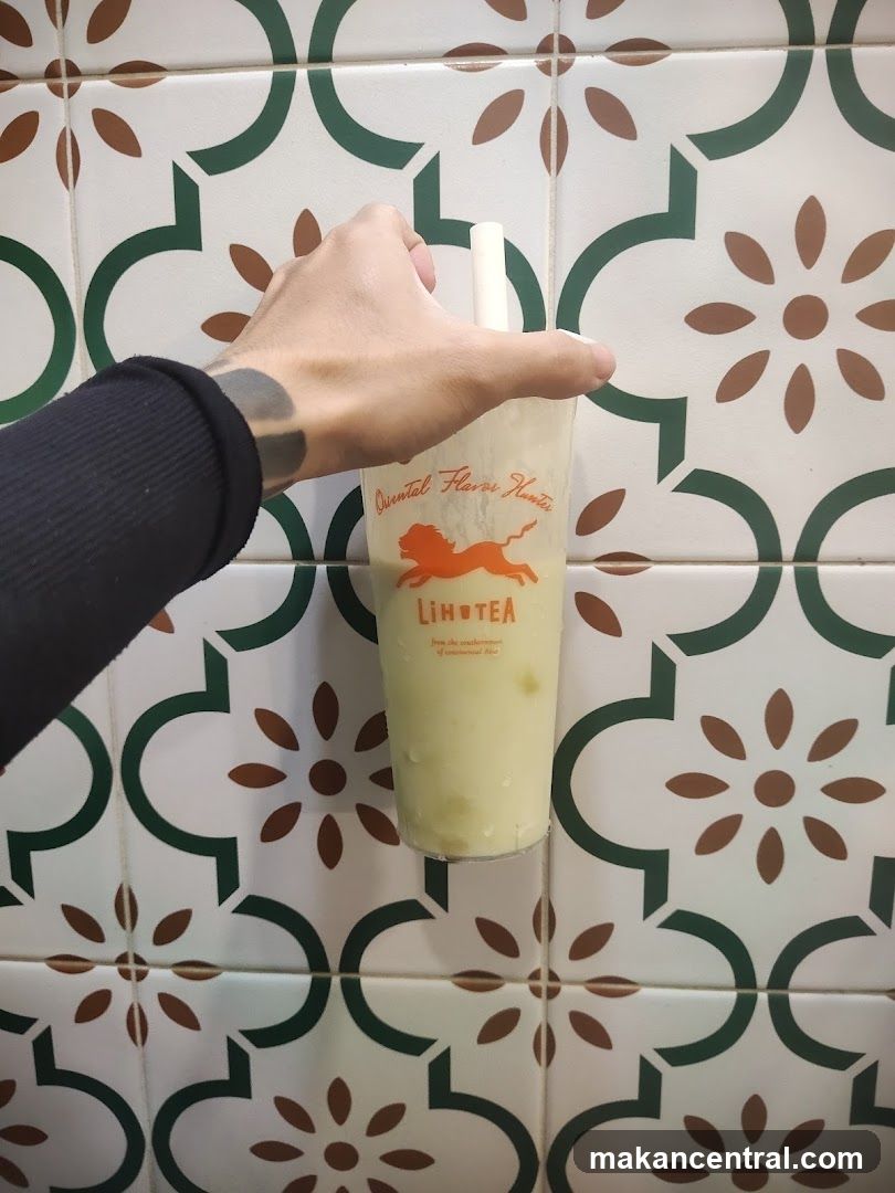 Hand holding drink in front of tiled wall