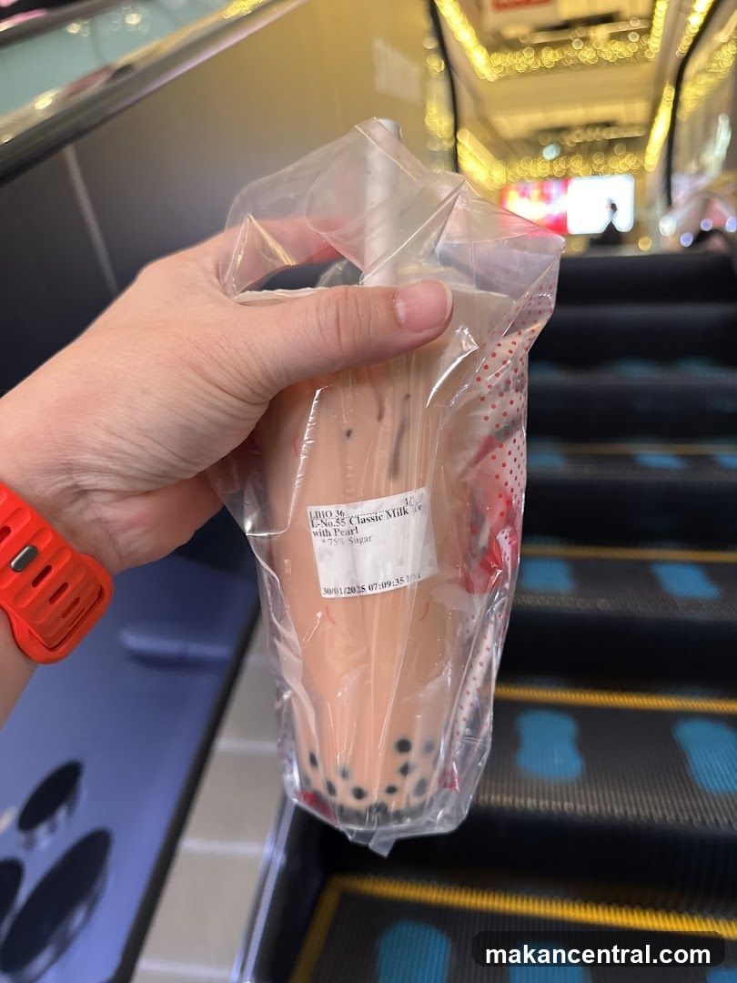 Hand holding bubble tea on escalator