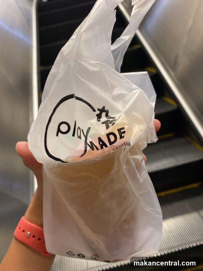 Hand holding packaged drink on escalator