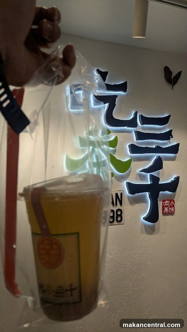 Hand holding drink in front of illuminated sign