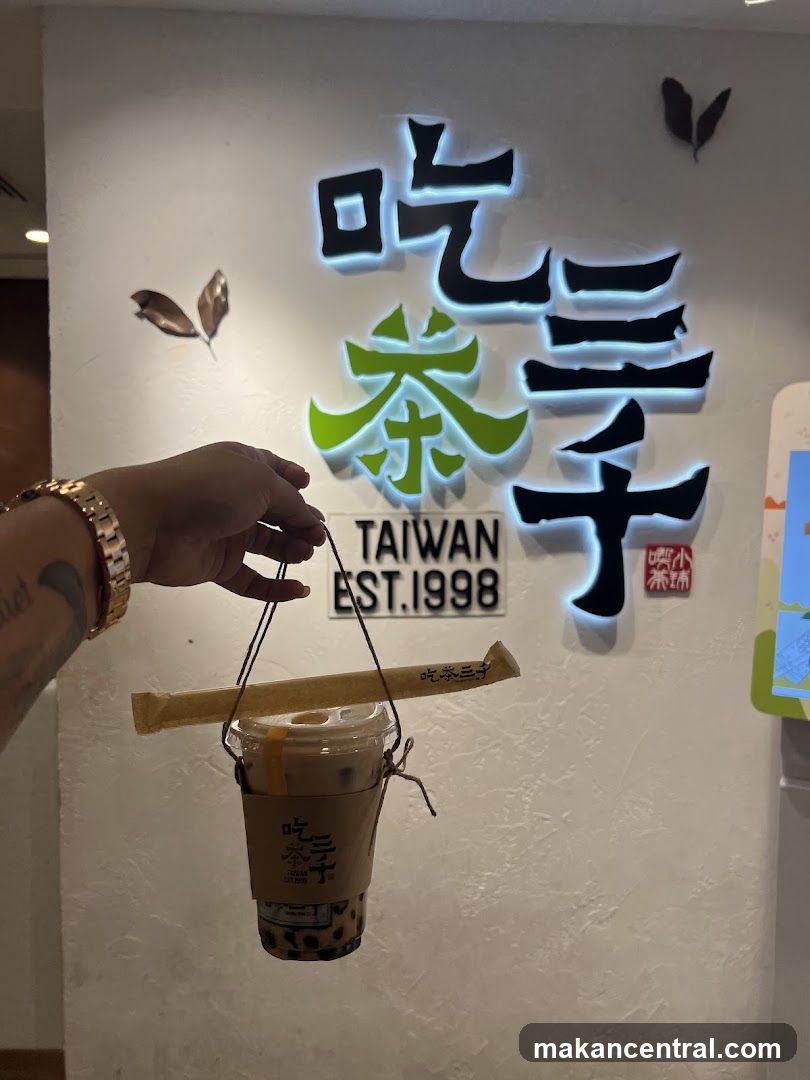 Hand holding drink in front of illuminated sign