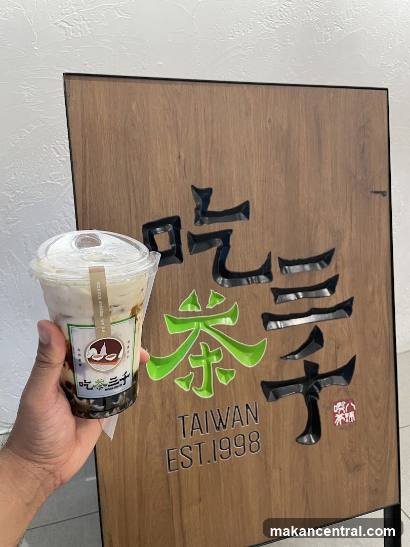 Hand holding drink in front of sign