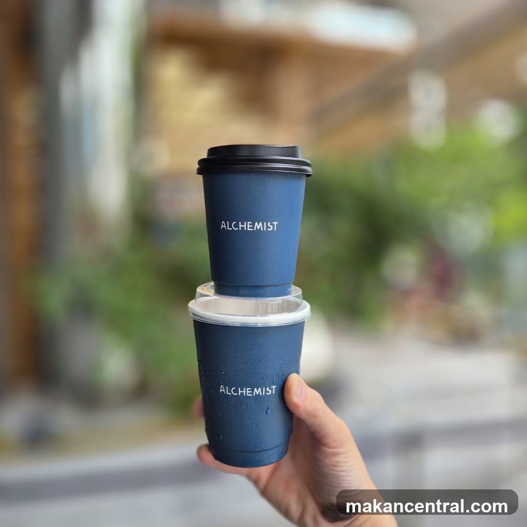 Hand holding two Alchemist coffee cups