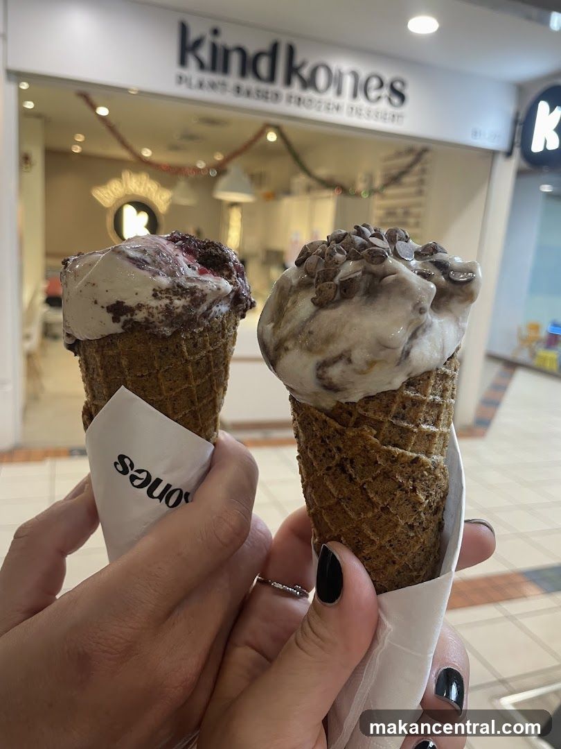 Hands holding ice cream cones in front of Kind Kones storefront