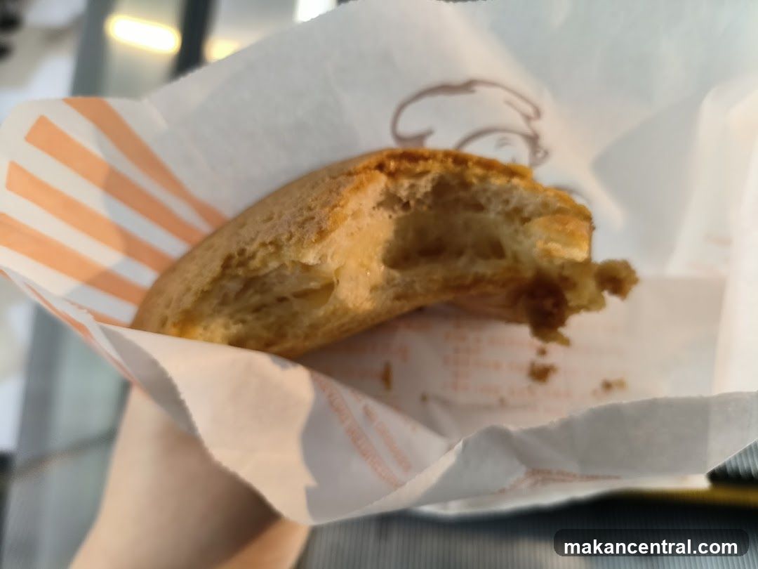 Hand holding partially eaten pastry wrapped in paper