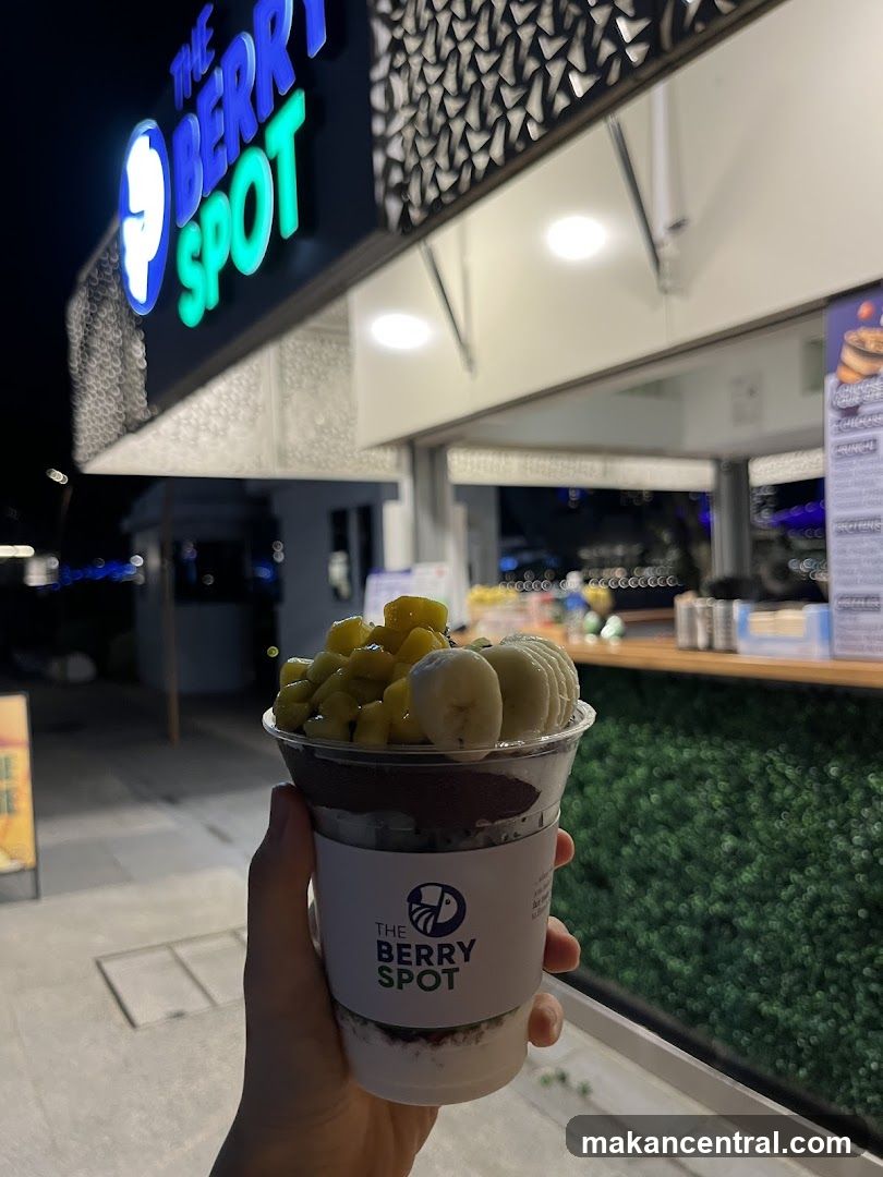 Hand holding berry dessert in front of The Berry Spot storefront