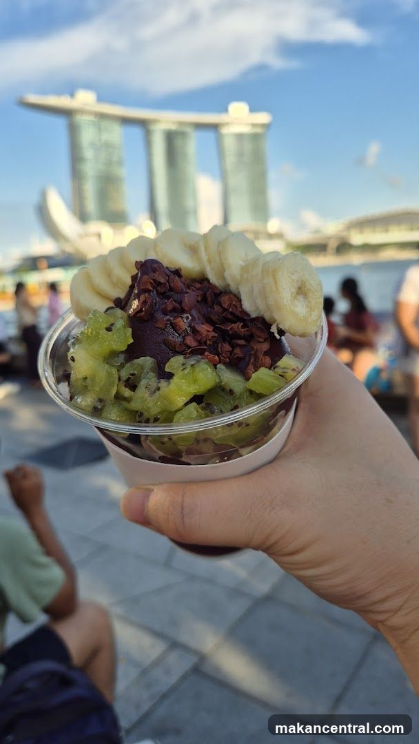 Hand holding a fruit bowl dessert with Marina Bay Sands in background