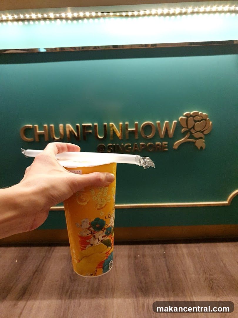 Hand holding drink in front of Chunfunhow @ Singapore sign