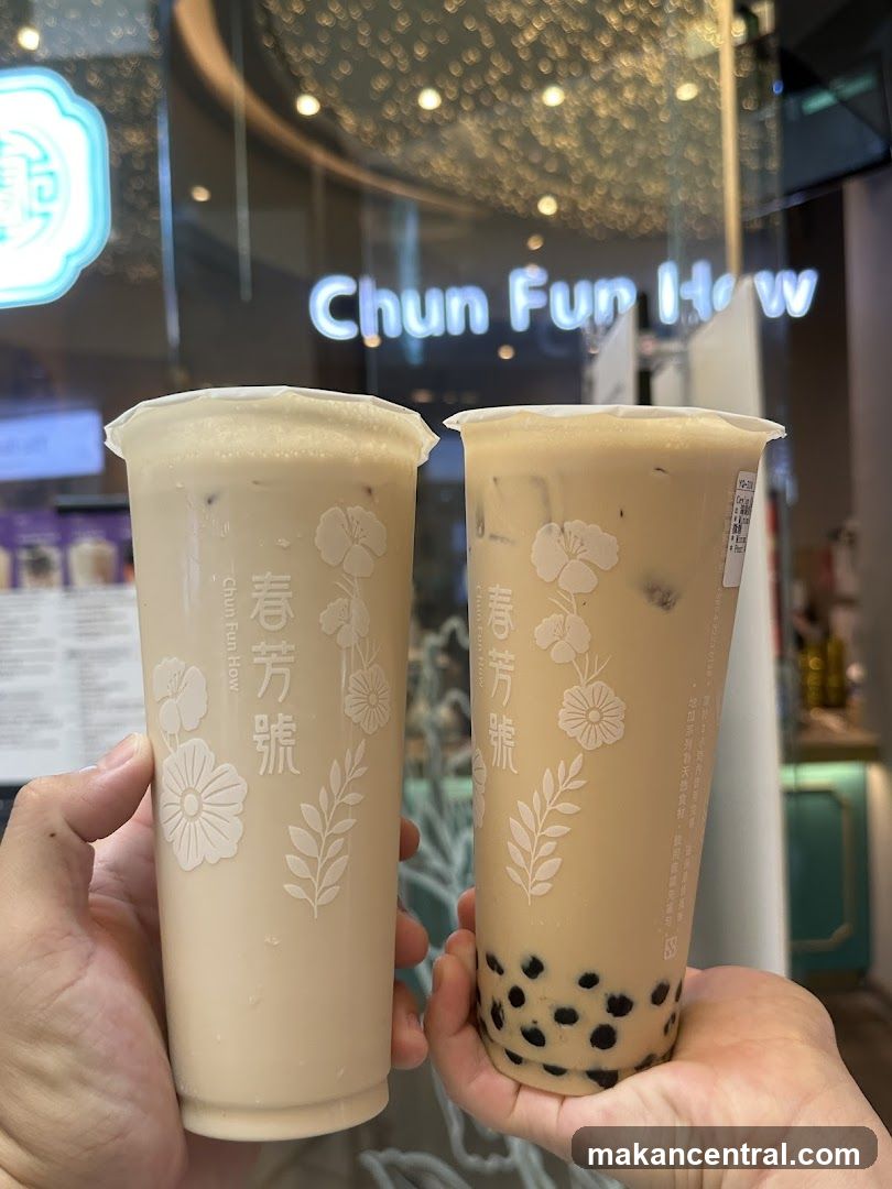 Two bubble tea drinks held in front of Chun Fun How storefront