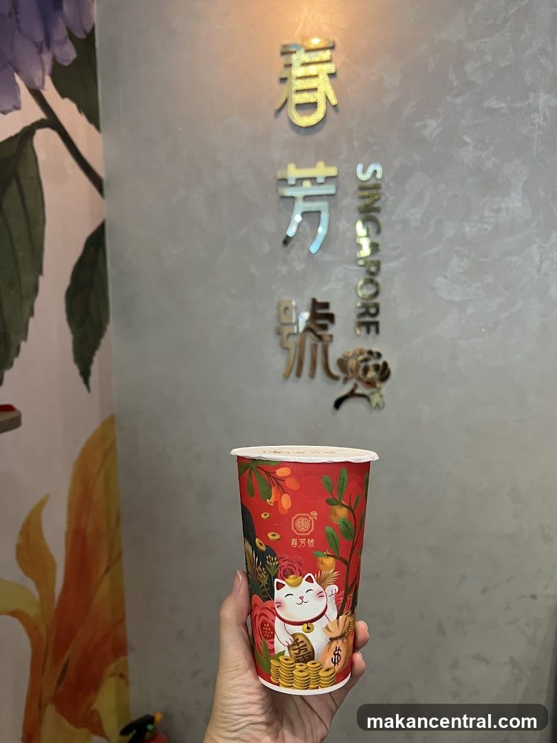 Hand holding a branded cup in front of wall signage