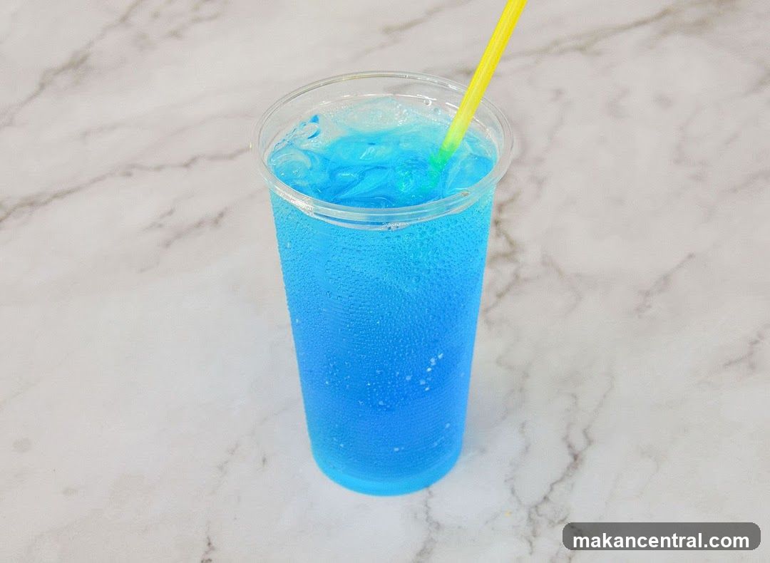 Blue beverage in plastic cup with straw