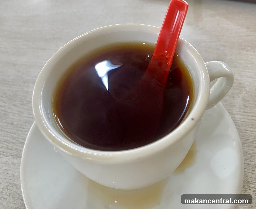 Cup of dark beverage with red spoon