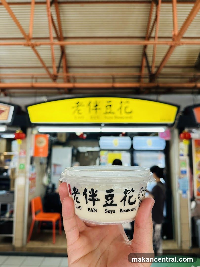 Hand holding soya beancurd cup in front of shop