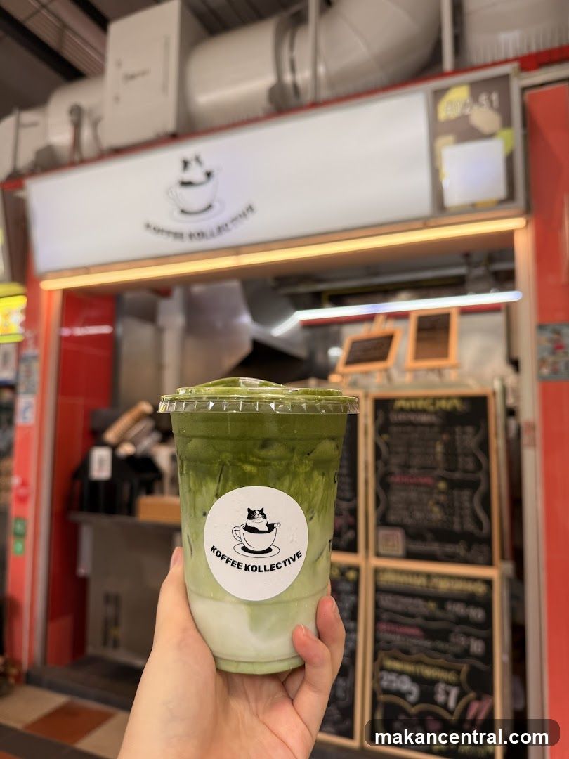 Hand holding matcha drink in front of Koffee Kollektive storefront