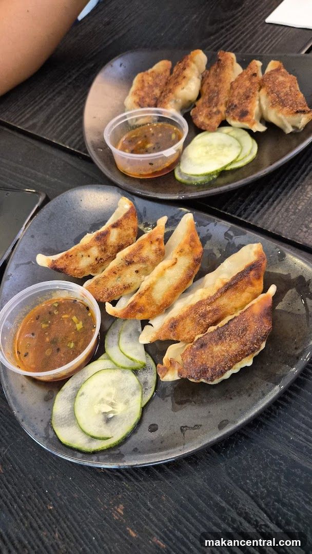 Pan-fried dumplings with dipping sauce and cucumber slices
