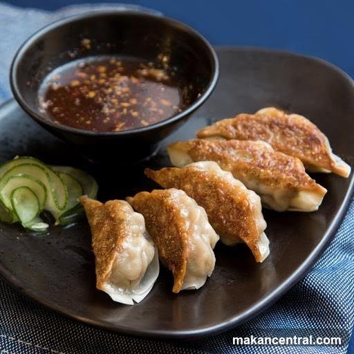 Pan-fried dumplings with dipping sauce and cucumber slices