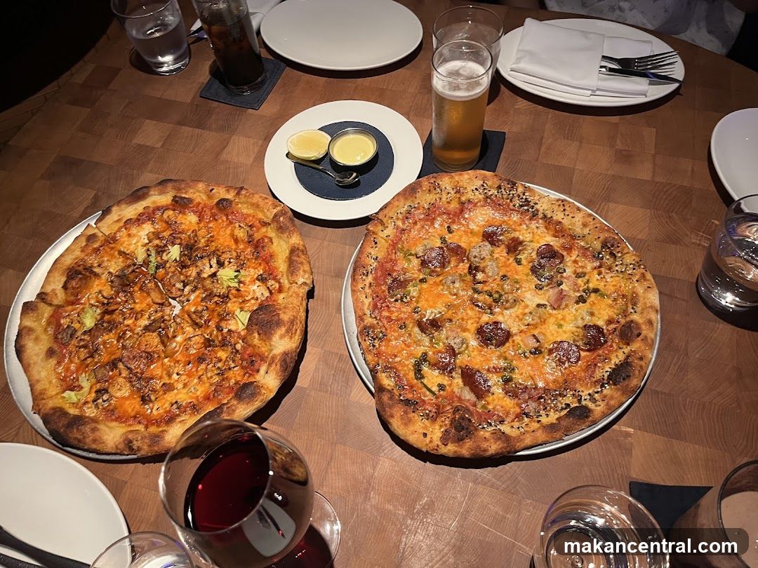 Two Pizzas and Drinks on a Wooden Table