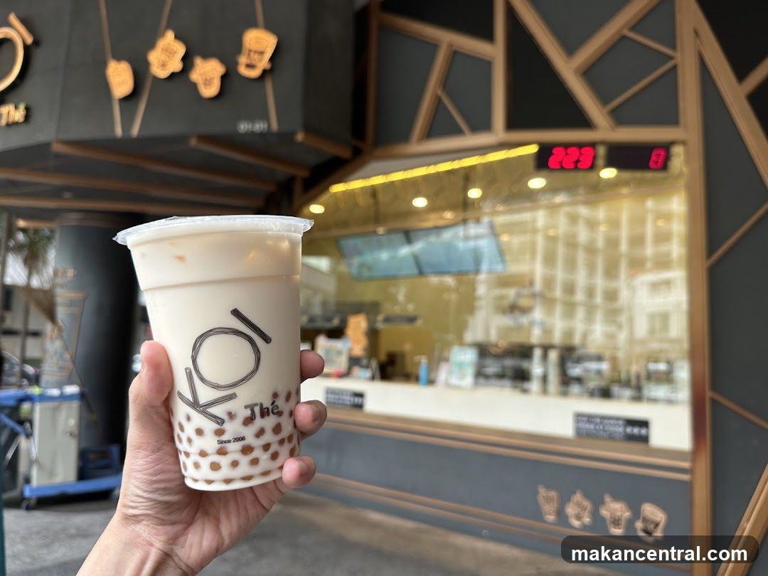 Hand holding a bubble tea drink in front of a shop