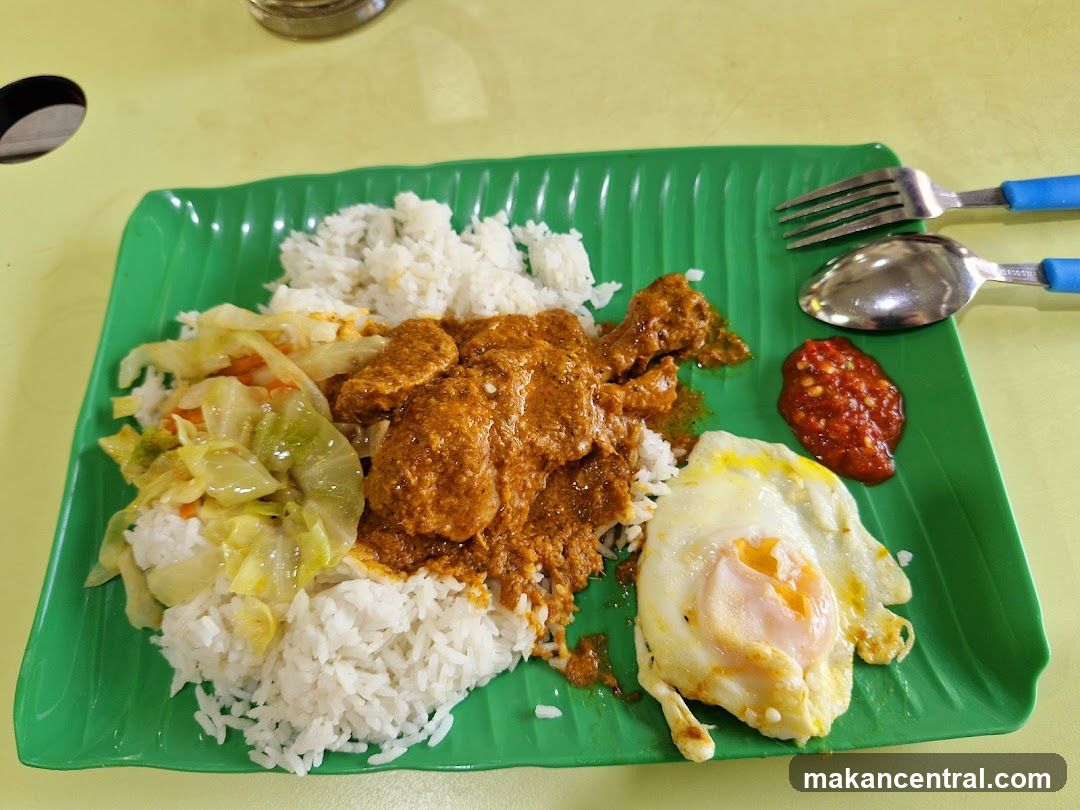 Rice plate with curry chicken, fried egg, and vegetables