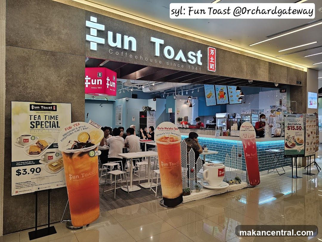 The exterior of a Fun Toast coffeehouse with its prominent signage. Inside, customers are seated at tables, and staff are visible behind the counter. Large promotional cutouts of drinks and a menu board are displayed.