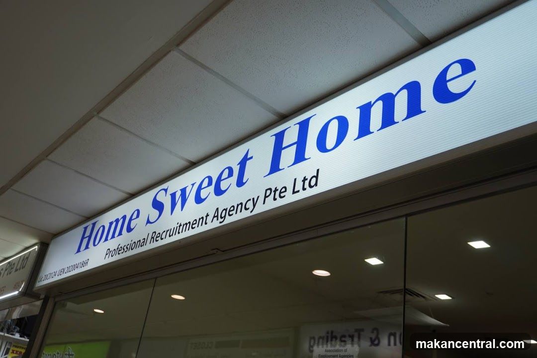 A lit sign with blue text reads "Home Sweet Home" and below it "Professional Recruitment Agency Pte Ltd". The sign is mounted above a glass storefront.