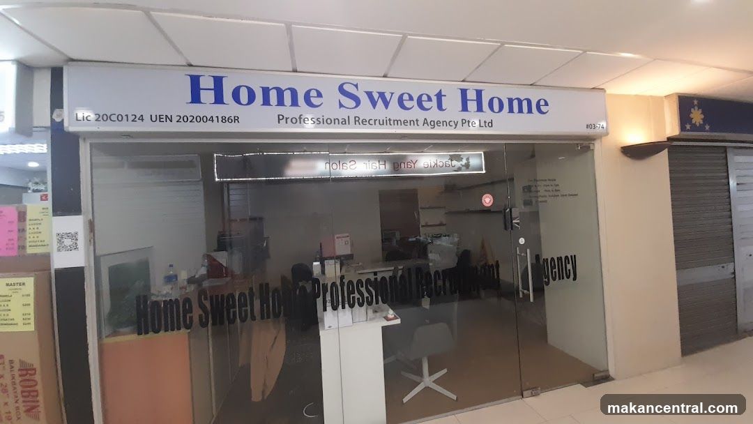The exterior of a recruitment agency with a glass door and windows. The business name "Home Sweet Home" and "Professional Recruitment Agency Pte Ltd" are visible on a sign above the entrance and also on the glass door. Inside, office furniture and equipment can be seen.