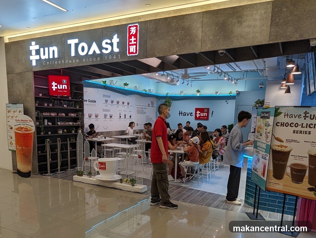 The exterior of a Fun Toast coffeehouse with its prominent signage. Inside, customers are seated at tables, and a menu board displays various drinks and promotions.
