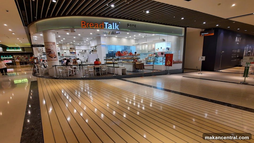 A BreadTalk bakery and cafe with a display of baked goods and seating for customers. The storefront has the BreadTalk logo prominently displayed above the entrance.