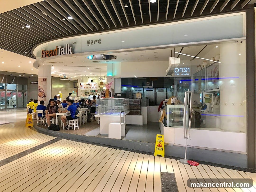 A BreadTalk bakery and cafe with seating for customers. The storefront features large glass windows and a prominent "BreadTalk" sign. Inside, customers are seated at tables, and baked goods are displayed.