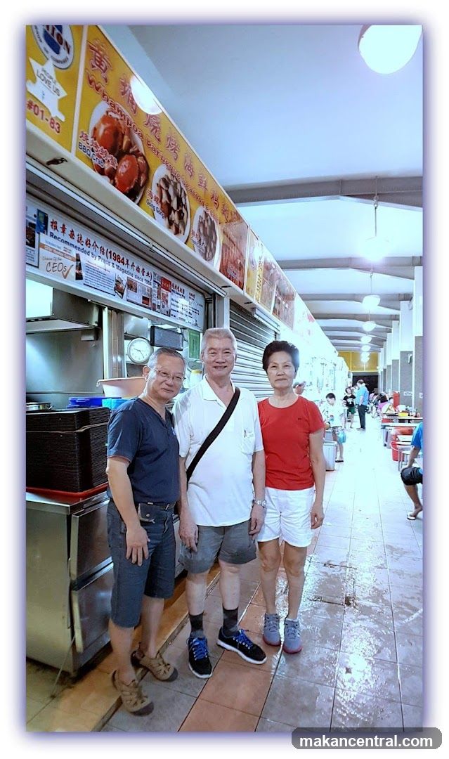 Three people in front of a food stall