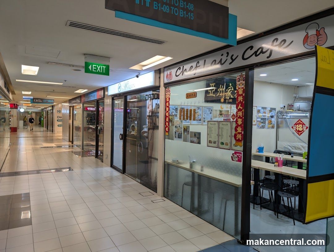 The exterior of a cafe with a sign that reads "Chef Lai's Cafe". Inside, there are tables and chairs, and a menu is visible on the wall.