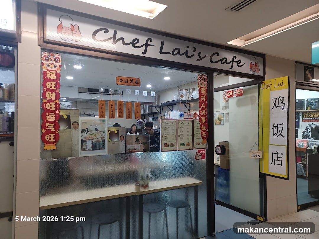 The exterior of a cafe with a sign that reads "Chef Lai's Cafe". There are menus displayed on the window and a sign with Chinese characters that says "Chicken Rice Shop".