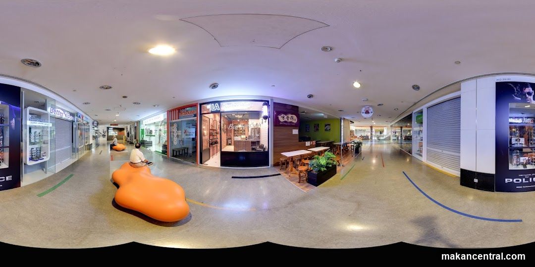 Indoor shopping mall corridor with various shops and seating areas