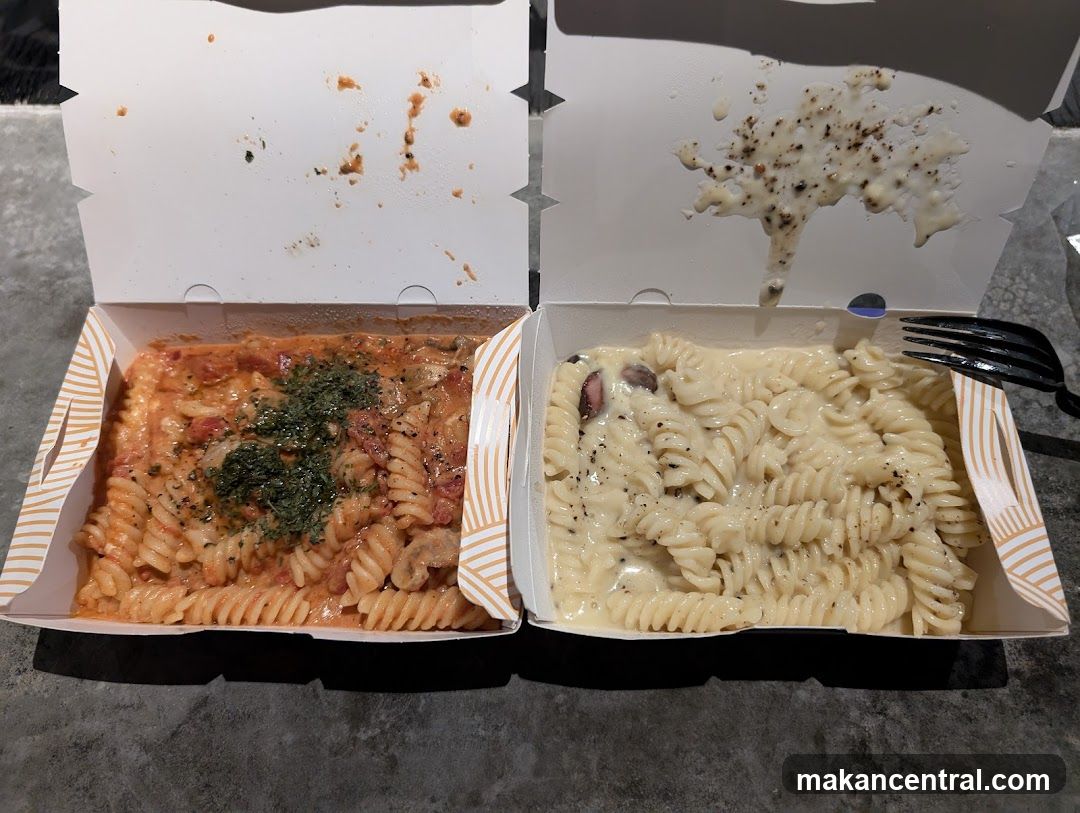 Two pasta dishes in takeout boxes