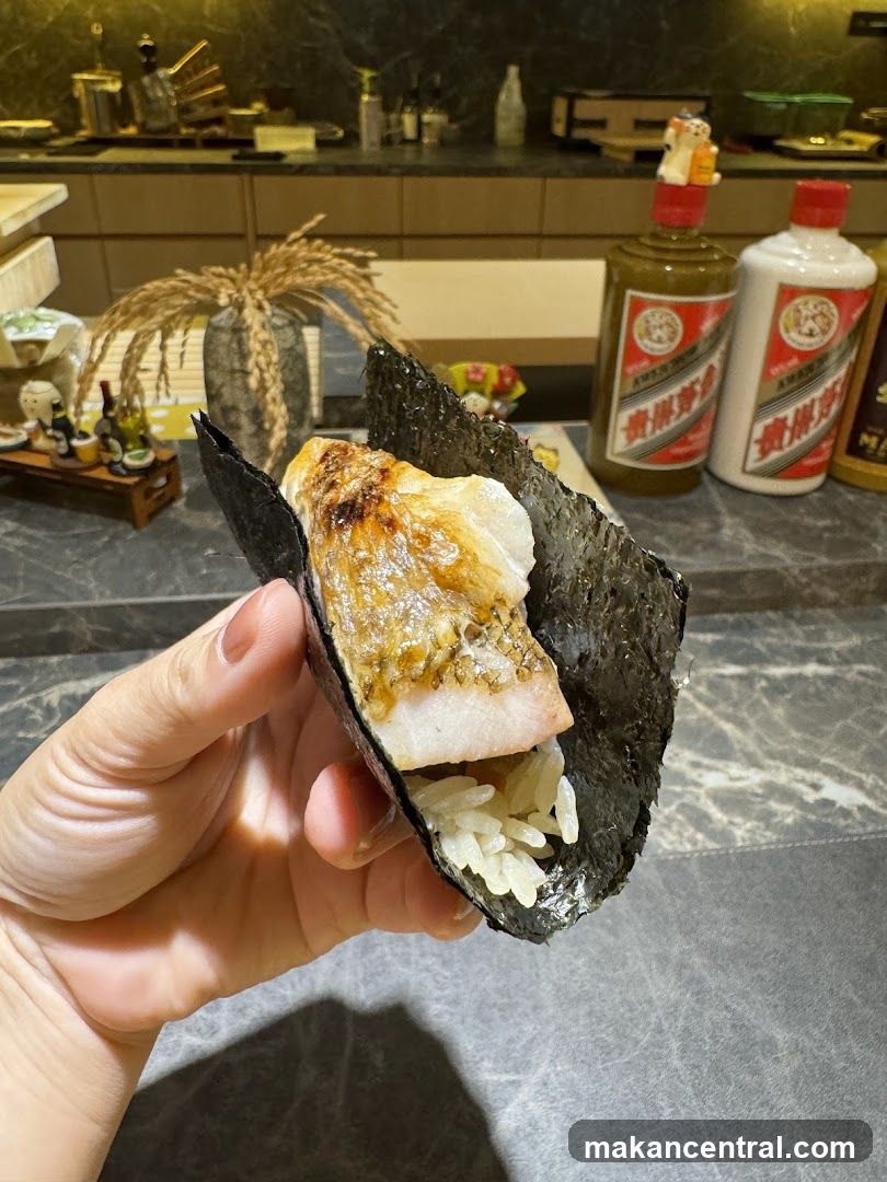 Hand holding a piece of sushi wrapped in seaweed