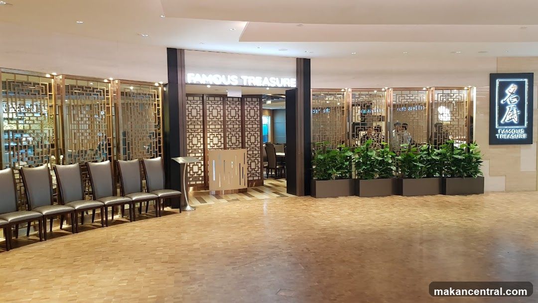 The exterior entrance of a restaurant called "Famous Treasure" is visible. The entrance features ornate golden screens and a row of chairs. A sign with the restaurant's name in English and Chinese characters is displayed on the right side of the facade.