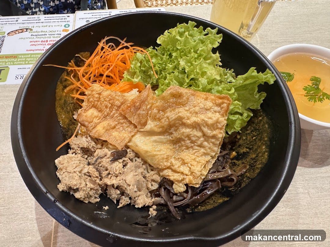 Bowl of food with shredded carrots, lettuce, fried tofu skin, and minced meat