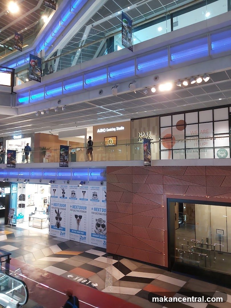 Interior of a shopping mall with various storefronts and advertisements