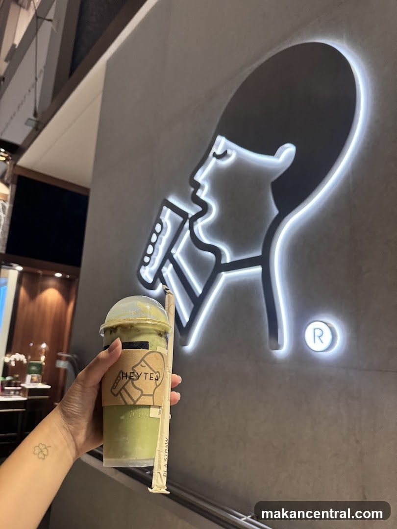Person holding a drink in front of a logo