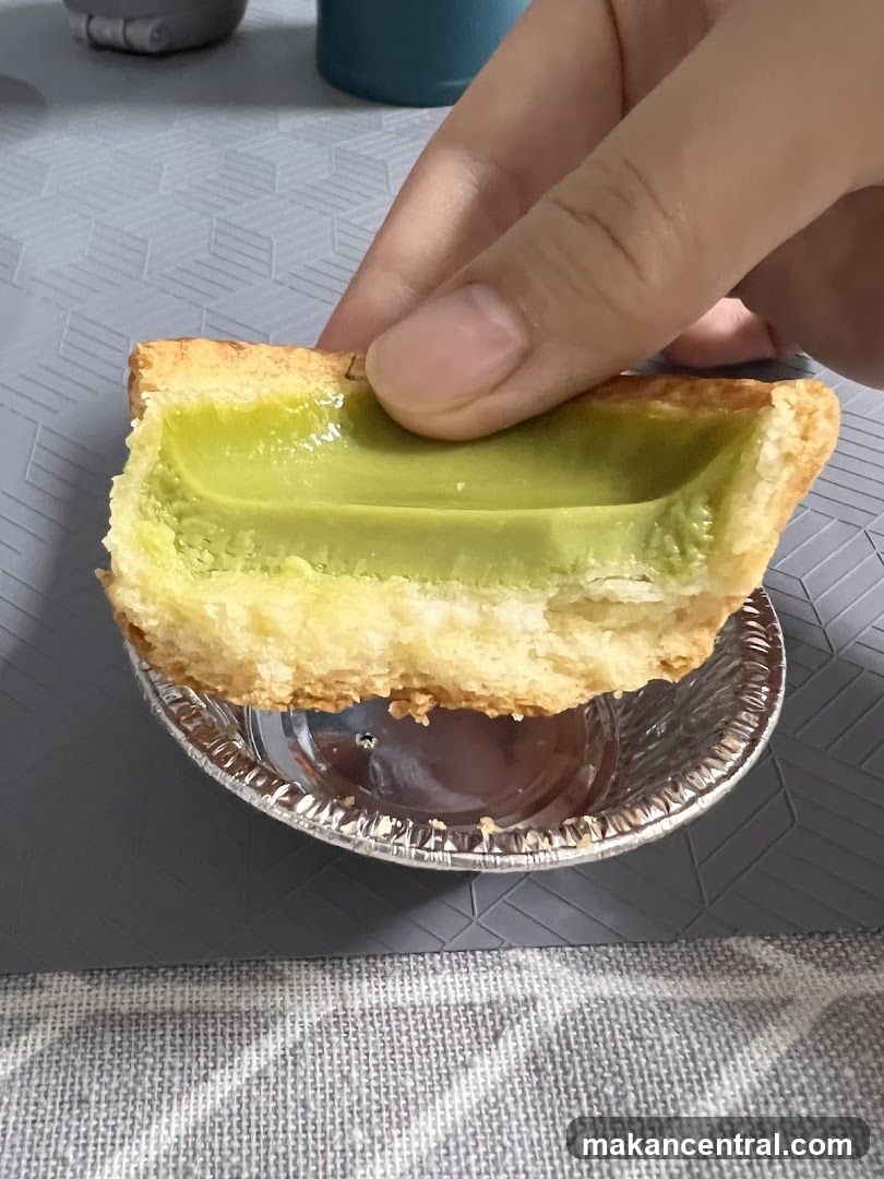 Close-up of a hand holding a green custard tart