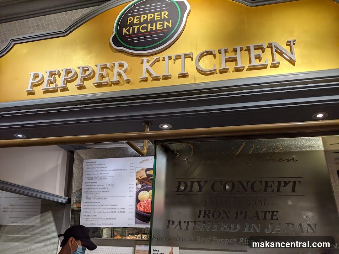 The exterior of a Pepper Kitchen restaurant. The sign above the entrance reads "PEPPER KITCHEN" in large silver letters. Below the sign, etched into a metallic surface, is "Pepper Kitchen DIY CONCEPT USING SPECIAL IRON PLATE PATENTED IN JAPAN". A menu is visible to the left.