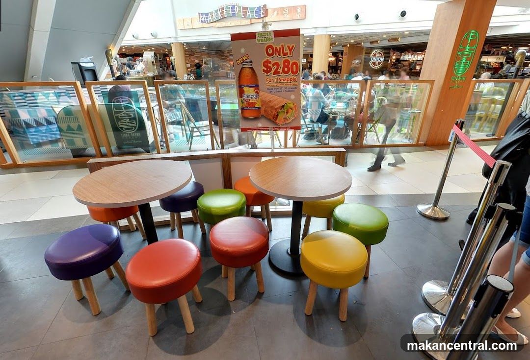 Food court seating area with promotional poster