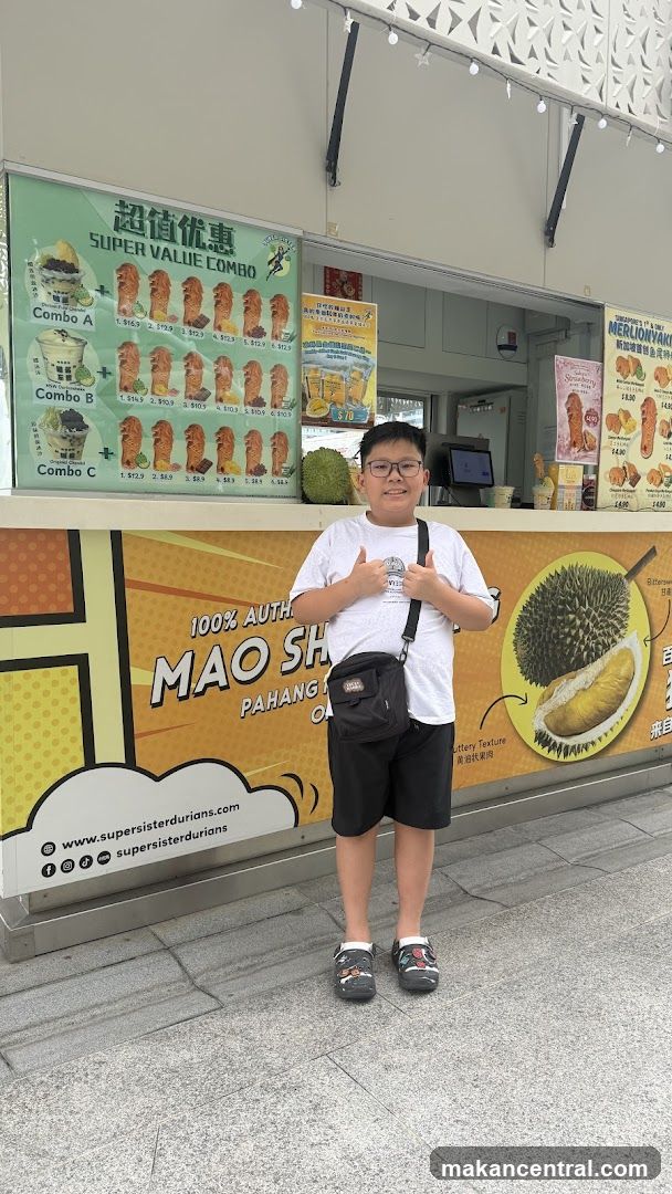 Boy giving thumbs up in front of a durian dessert stall