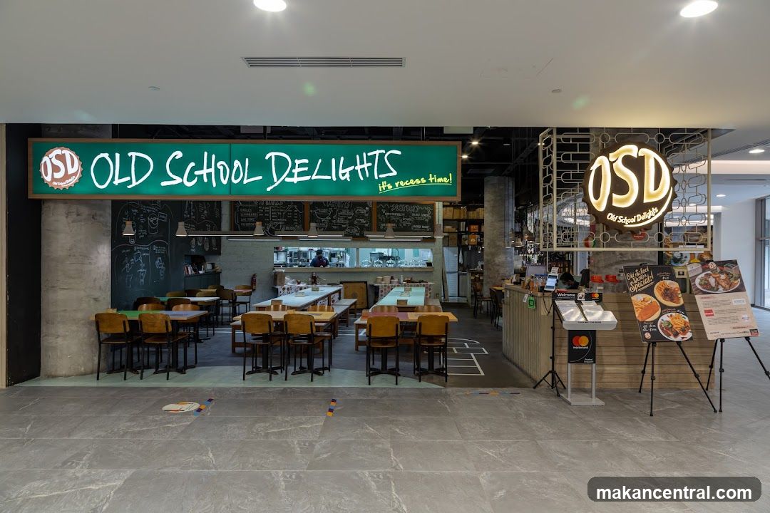 The exterior of a restaurant called Old School Delights. A large green sign above the entrance reads "OLD SCHOOL DELIGHTS it's recess time!". Inside, tables and chairs are visible, along with a kitchen area. A circular OSD logo is also displayed.