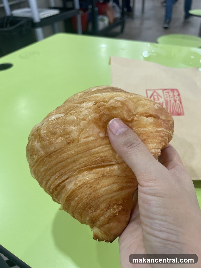 Hand holding croissant at a food stall