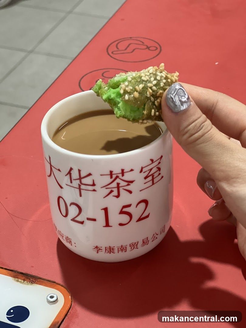 Hand holding green sesame snack over tea cup