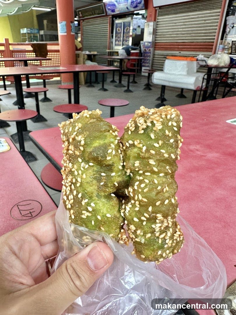 Hand holding green sesame snack at food court
