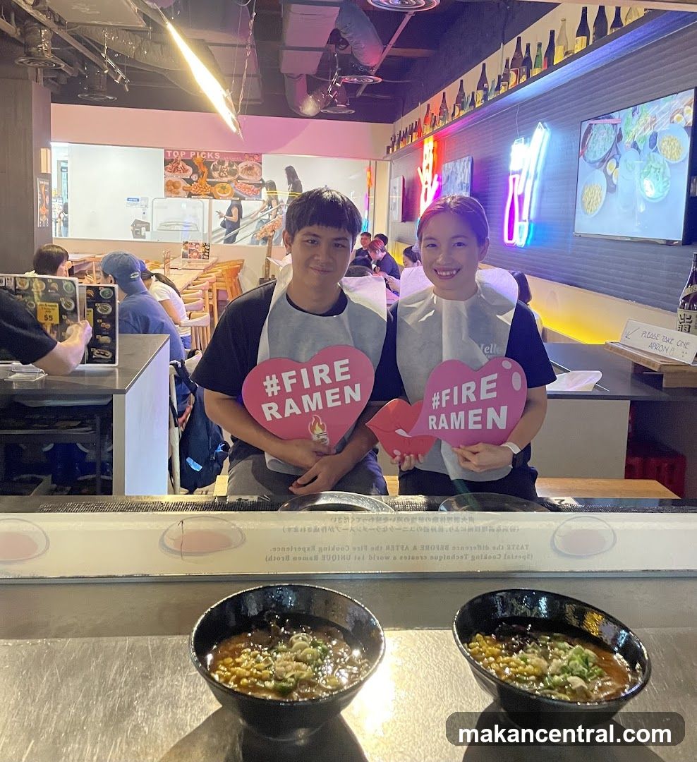 Two staff members holding promotional signs at a ramen restaurant counter